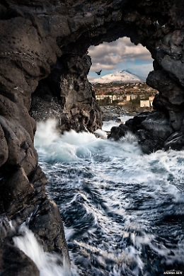 Suggestivo scatto dell'Etna incorniciato da un arco di roccia lavica