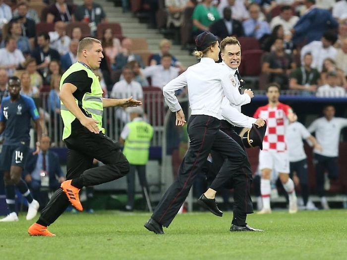 epa06891023 Two pitch invaders are chased by a steward during the FIFA World Cup 2018 final between France and Croatia in Moscow, Russia, 15 July 201