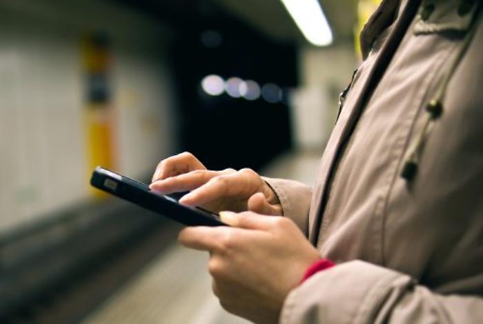 man-holding-smartphone-underground-station-500x336
