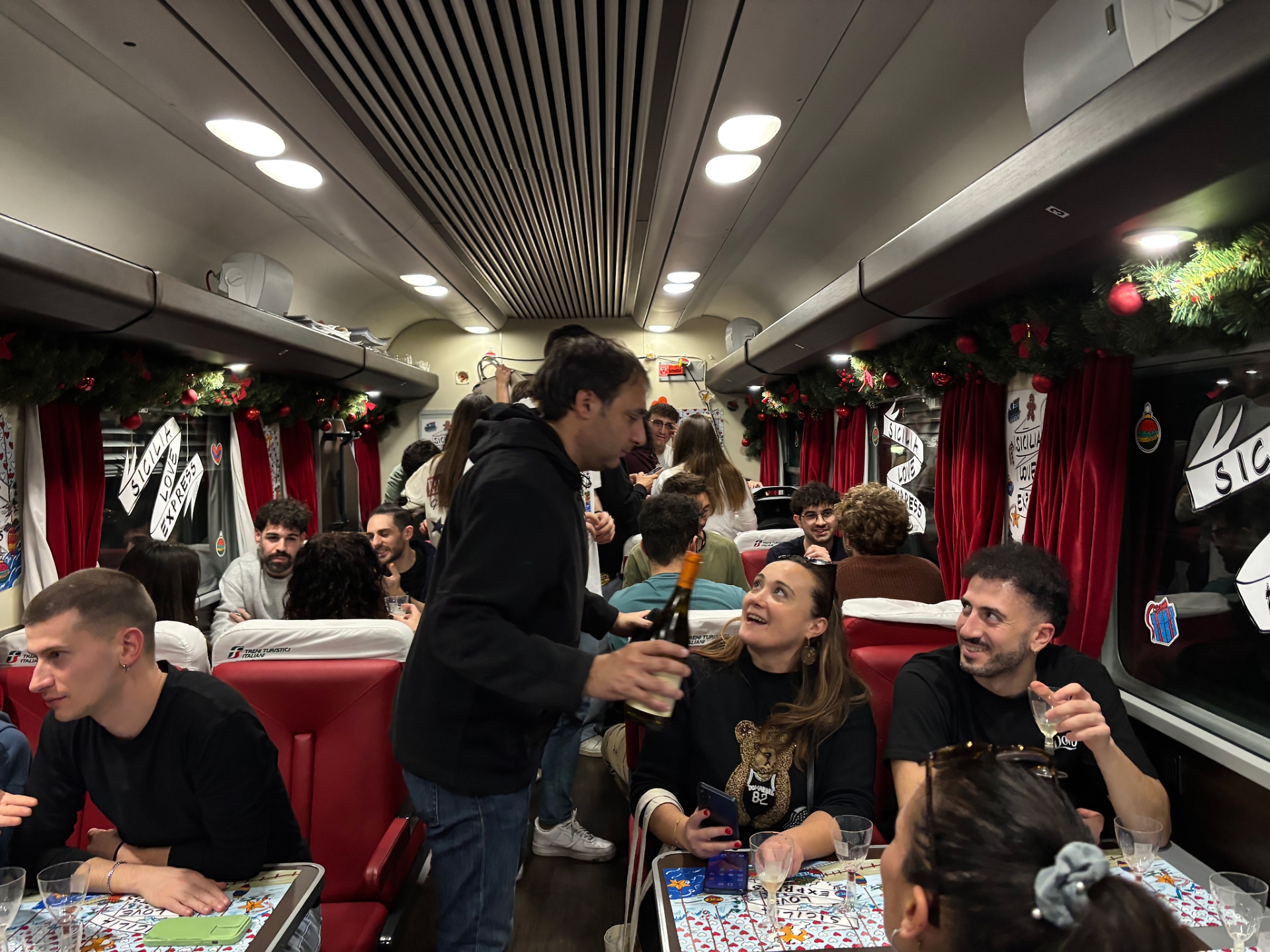 I passeggeri degustano vini siciliani nella carrozza 9